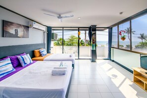 Een hotelkamer met twee bedden, een balkon met uitzicht op zee en een plafondventilator.