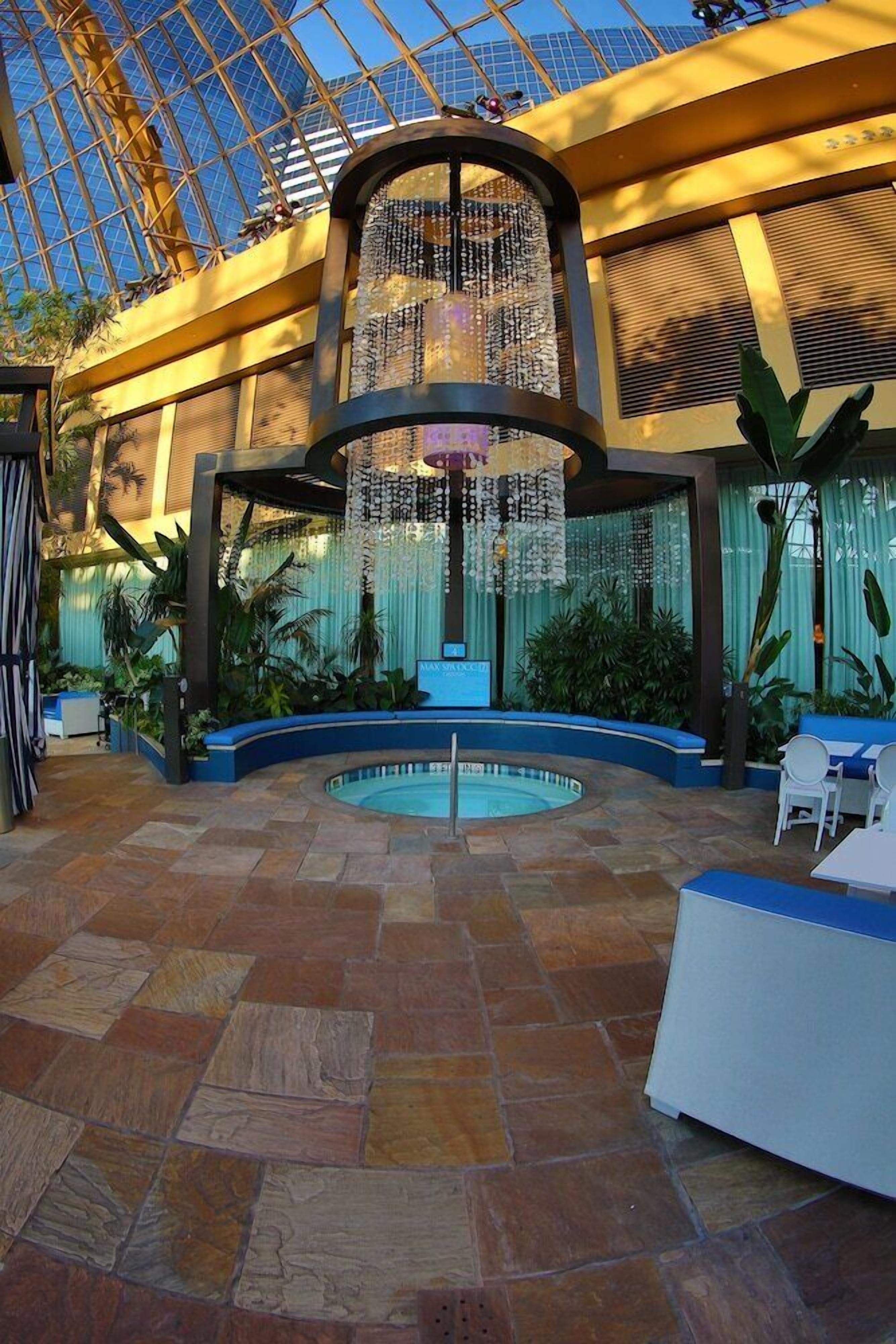 A spacious atrium with a central pool, surrounded by seating areas and lush greenery.