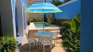 A patio with a pool, white metal chairs, and a blue umbrella. - Casa Azulí Santiago  (Mérida)