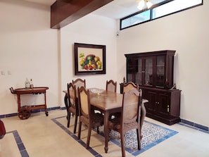 A dining area with a wooden table and chairs, a cabinet, and a wall-mounted painting.