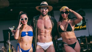 Three people in swimwear at an outdoor venue with a sign in the background. - SUNSET BEACH (Cartagena)