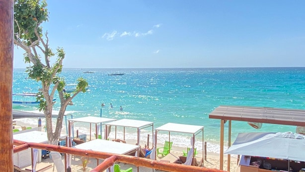 A beachside area with wooden structures, including tables and chairs, overlooking the sea. - SUNSET BEACH (Cartagena)