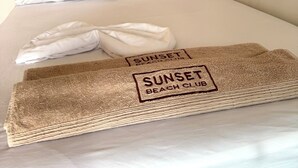A neatly made bed with a folded towel and a beach-themed blanket, a bamboo headboard, and a motivational quote on the wall. - SUNSET BEACH (Cartagena)