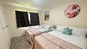 A bedroom with two beds, a window with curtains, a wall-mounted picture, and a carpeted floor.