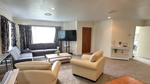 A living room with a sofa, two armchairs, a coffee table, and a TV.