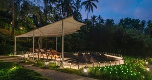 An outdoor seating area with a covered pavilion, surrounded by lush greenery and palm trees. - Bobocabin Ubud (Tegallalang)