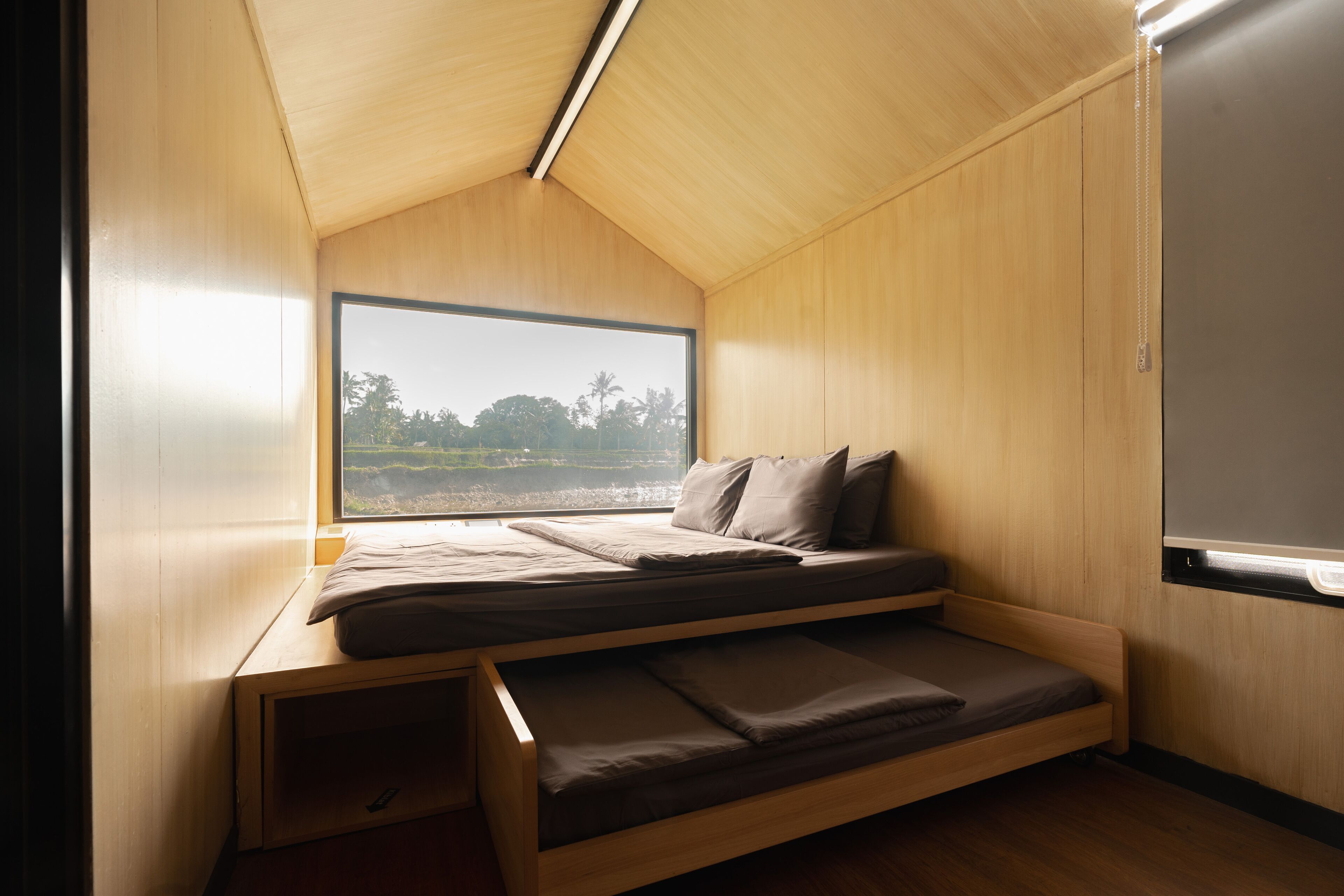 A compact bedroom with a bunk bed, a large window, and a skylight.