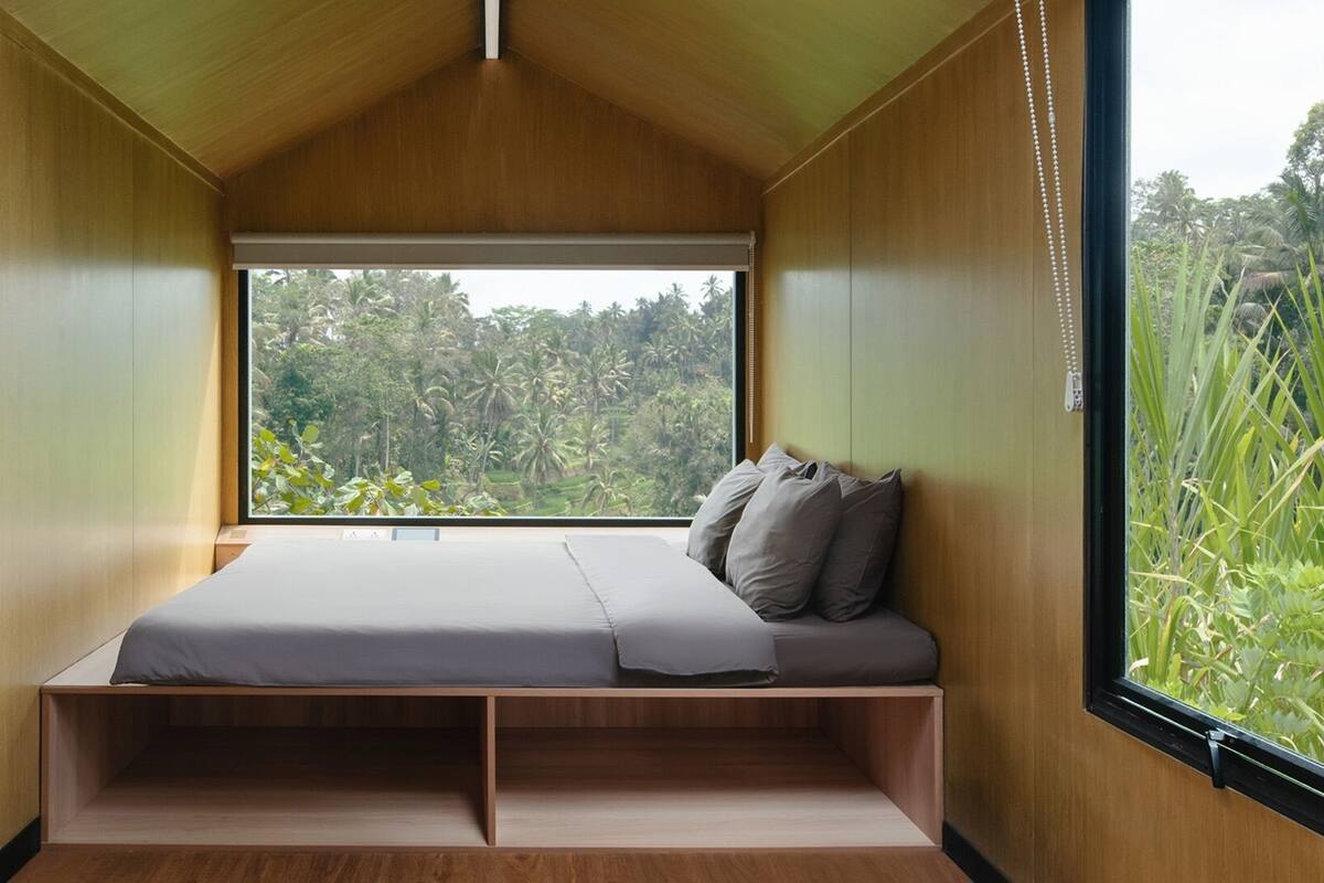 Un dormitorio pequeño con cama, ventana y vistas a zonas verdes.