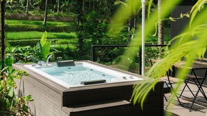 A hot tub in a lush garden with a wooden deck and a bench. - Bobocabin Ubud (Tegallalang)