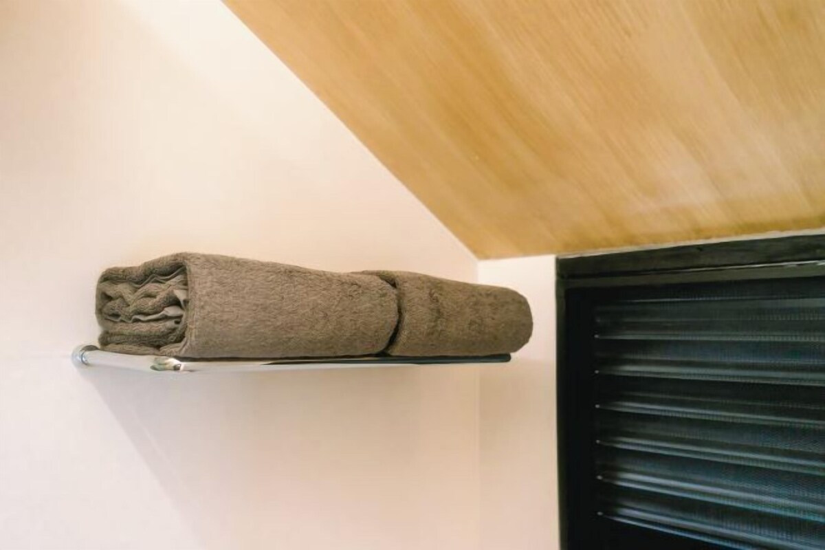 A towel on a shelf in a room with a wooden ceiling and a black shutter door.