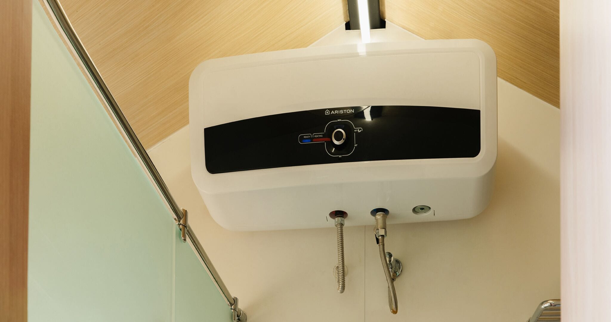 A white water heater with a digital display and two control knobs, mounted on a wall.