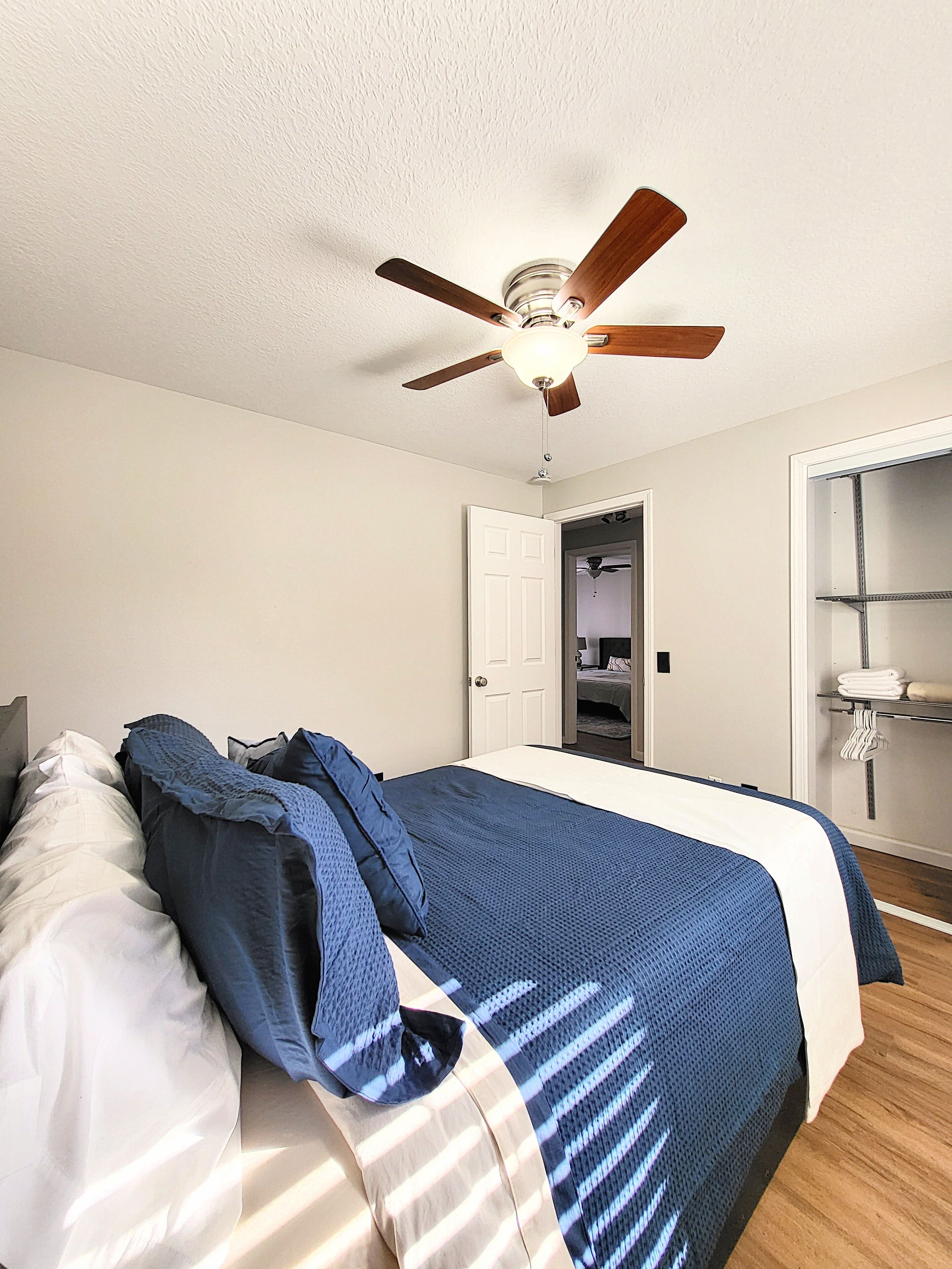 Ein Schlafzimmer mit Bett, Deckenventilator, weißer Tür und Kleiderschrank.