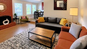 Ein Wohnzimmer mit Kamin, einer Couch, einem Couchtisch und einem Essbereich mit Stühlen und Tisch.