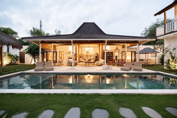Relax and unwind in our spacious outdoor living area with a pool, featuring a covered patio and comfortable seating.