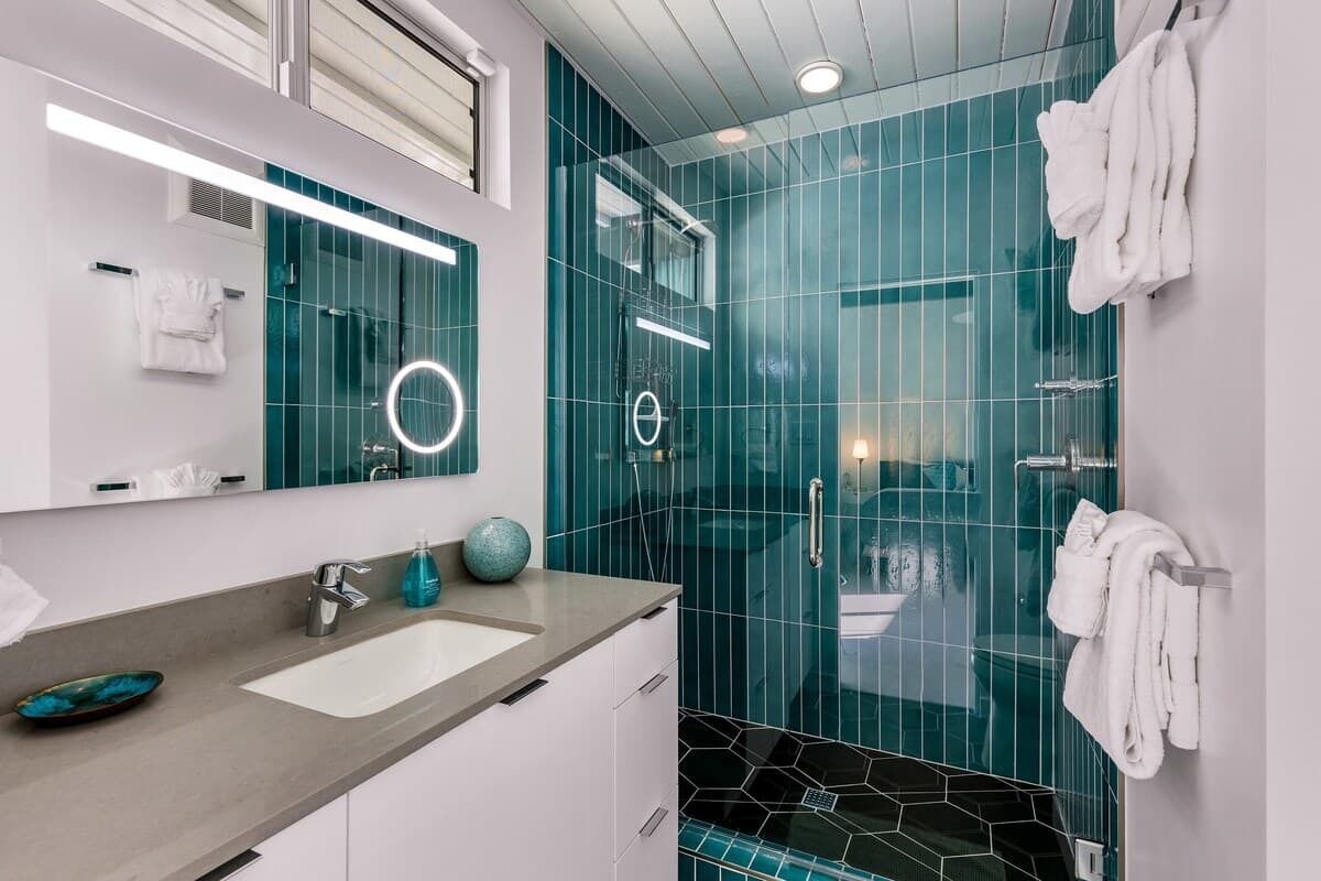 A modern bathroom with a glass shower enclosure, a vanity with a sink, and a mirror.