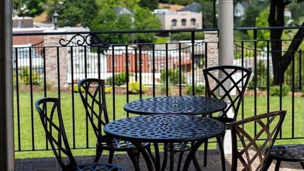 A patio with metal tables and chairs, a white column, and a view of a building with a dome in the background.