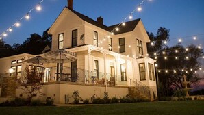 A two-story house with a covered porch and string lights.