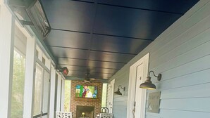 A covered porch with two striped ottomans, a wooden chest, and a brick fireplace. - Charming 3 BR, 2 Bath cabin located in quiet Clifftops and close to Sewanee (Monteagle)