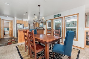 A spacious kitchen with wooden cabinets, a central island, and a dining area with a wooden table and blue chairs.