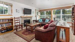 A living room with a fireplace, a television, a sofa, a coffee table, and a bookshelf. - Pacific Paradise-Comfortable, cute home near beach (Pacific City)