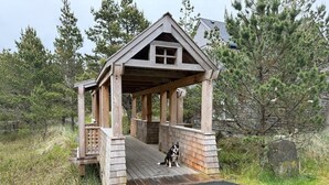 A wooden gazebo with a covered entrance and a dog sitting inside. - Pacific Paradise-Comfortable, cute home near beach (Pacific City)