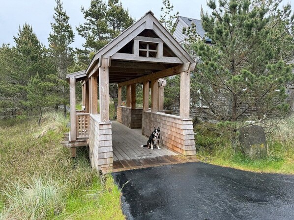 A wooden gazebo with a covered entrance and a dog sitting inside.