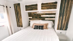 A bedroom with a large bed, a wooden headboard, and a window with curtains.