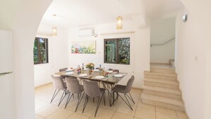 A dining area with a table set for four, surrounded by chairs, with a staircase leading to another level. - Protaras Holiday Villa My5 (Protaras)