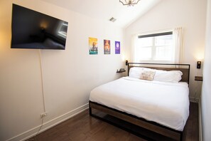 Quarto com cama, televisão de tela plana na parede e janela com cortinas.