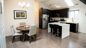 A modern kitchen with dark cabinets, stainless steel appliances, and a central island with bar stools. - Chicago Oasis | Spa Bath, Patio & Fireplace (Chicago)
