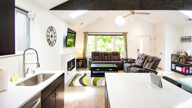 A modern living room with a sofa, a coffee table, and a dining area with a white table. - Chicago Oasis | Spa Bath, Patio & Fireplace (Chicago)