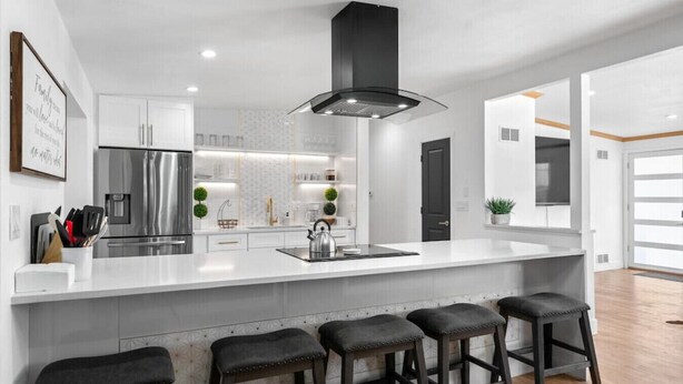 Uma cozinha moderna com uma ilha grande, eletrodomésticos de aço inoxidável e banquetas de bar.