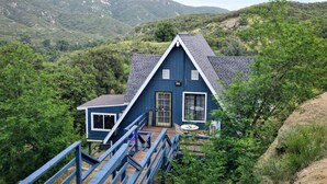 A blue house with a wooden deck and a staircase leading to the entrance. -  Cozy Chalet Retreat in Banning, California Pets-Friendly! (Banning)
