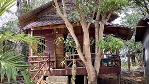 A rustic wooden house with a porch, surrounded by trees and vegetation. - Cocohuts Cambodia (Koh Rong Sanloem)