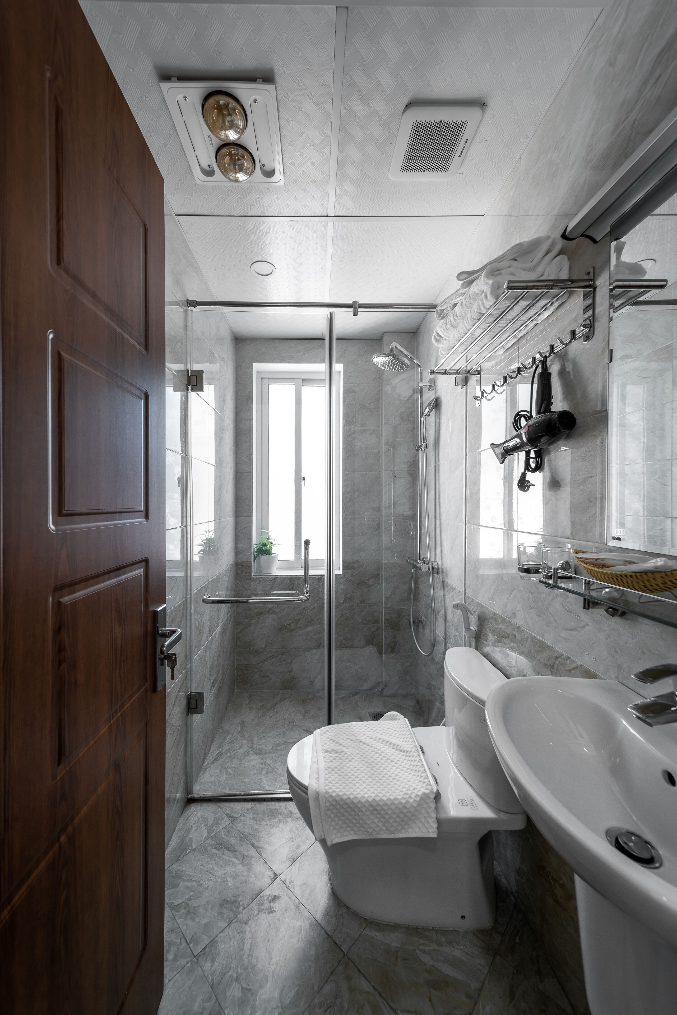 A modern bathroom with a glass shower enclosure, a white toilet, and a large sink.