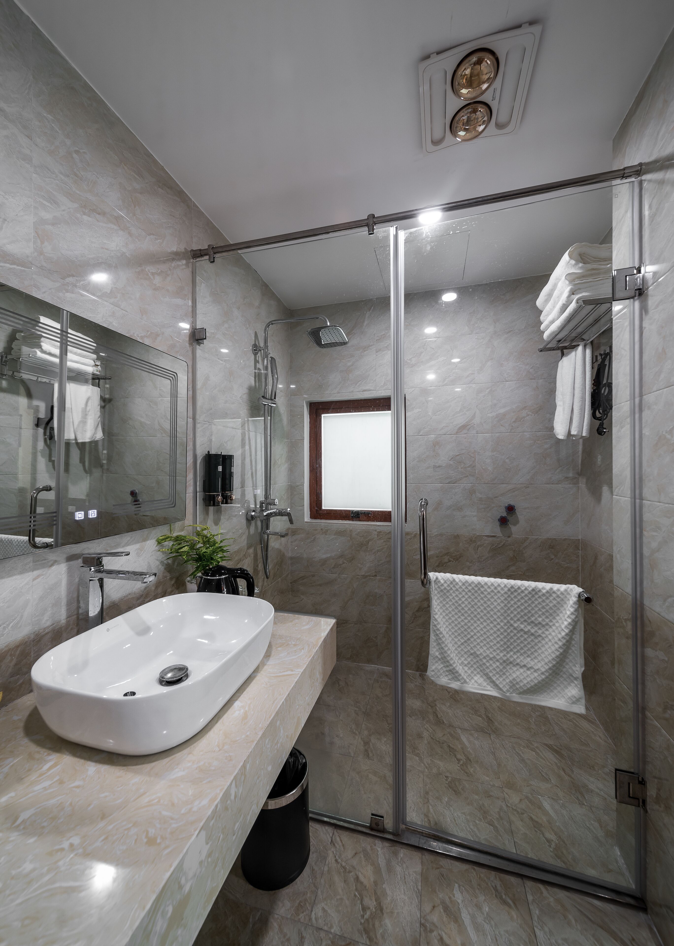 A modern bathroom with a glass-enclosed shower, a large sink, and a mirror.