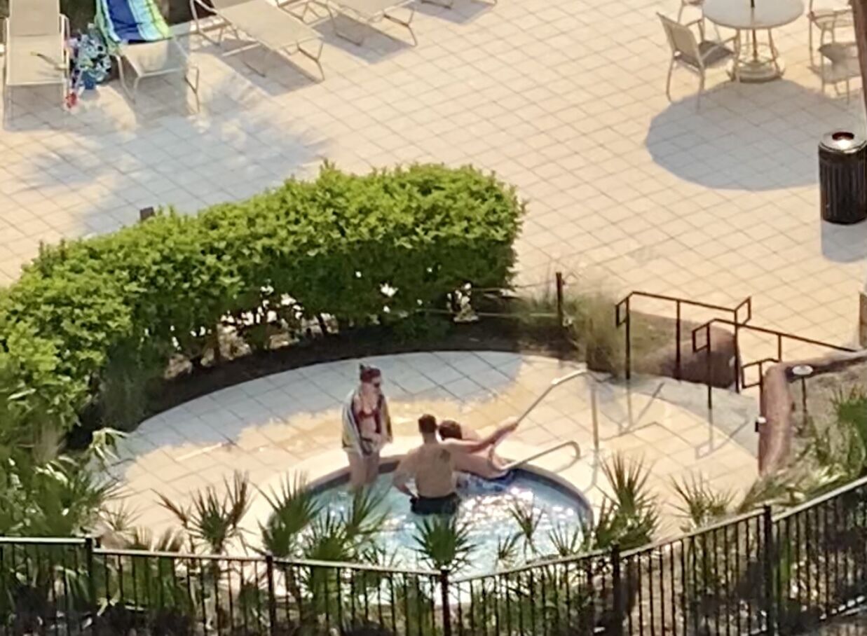 A swimming pool with lounge chairs and a small bridge.