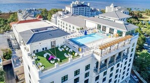 Ein Hochhotel mit Pool auf dem Dach, mehreren Balkonen und Blick auf den Ozean.
