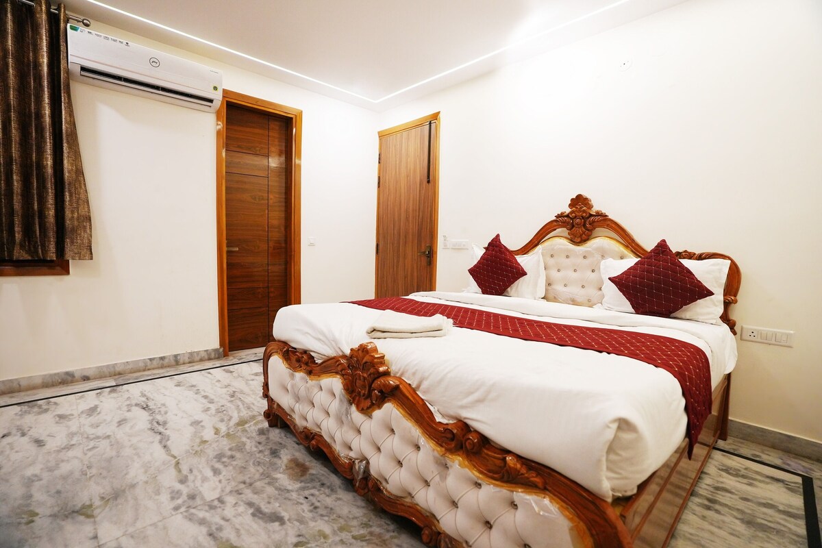 A bedroom with a large bed, wooden doors, and an air conditioning unit.