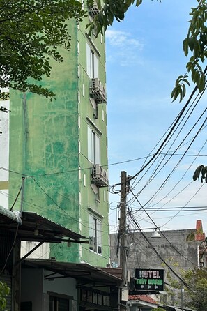A green building with a sign for a hotel named "HOTEL THINY DOORS." - Thuy Duong Hotel Binh Duong (Ho Chi Minh City)