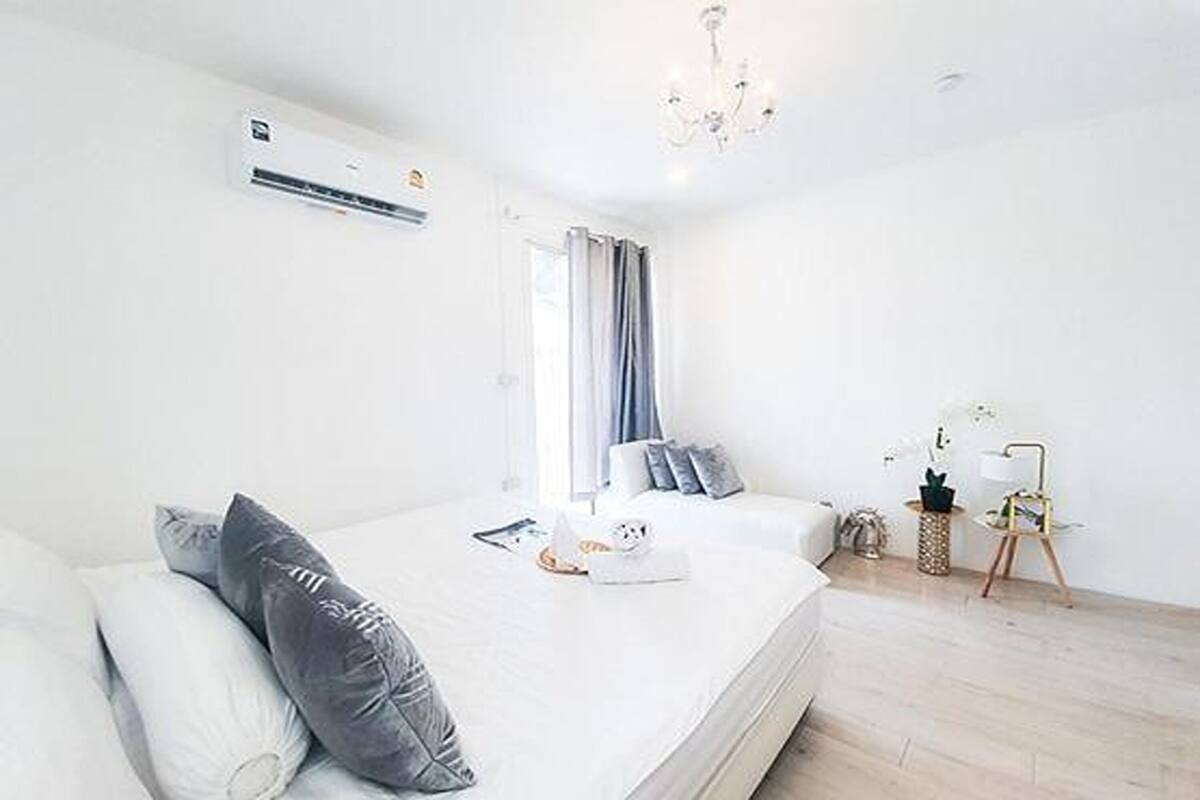 A modern bedroom with a bed, bedside table, and a small side table with a lamp.