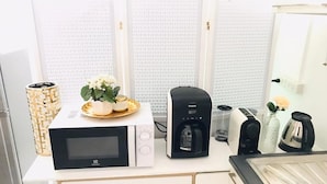 Una cocina con microondas, cafetera y un plato decorativo con flores.