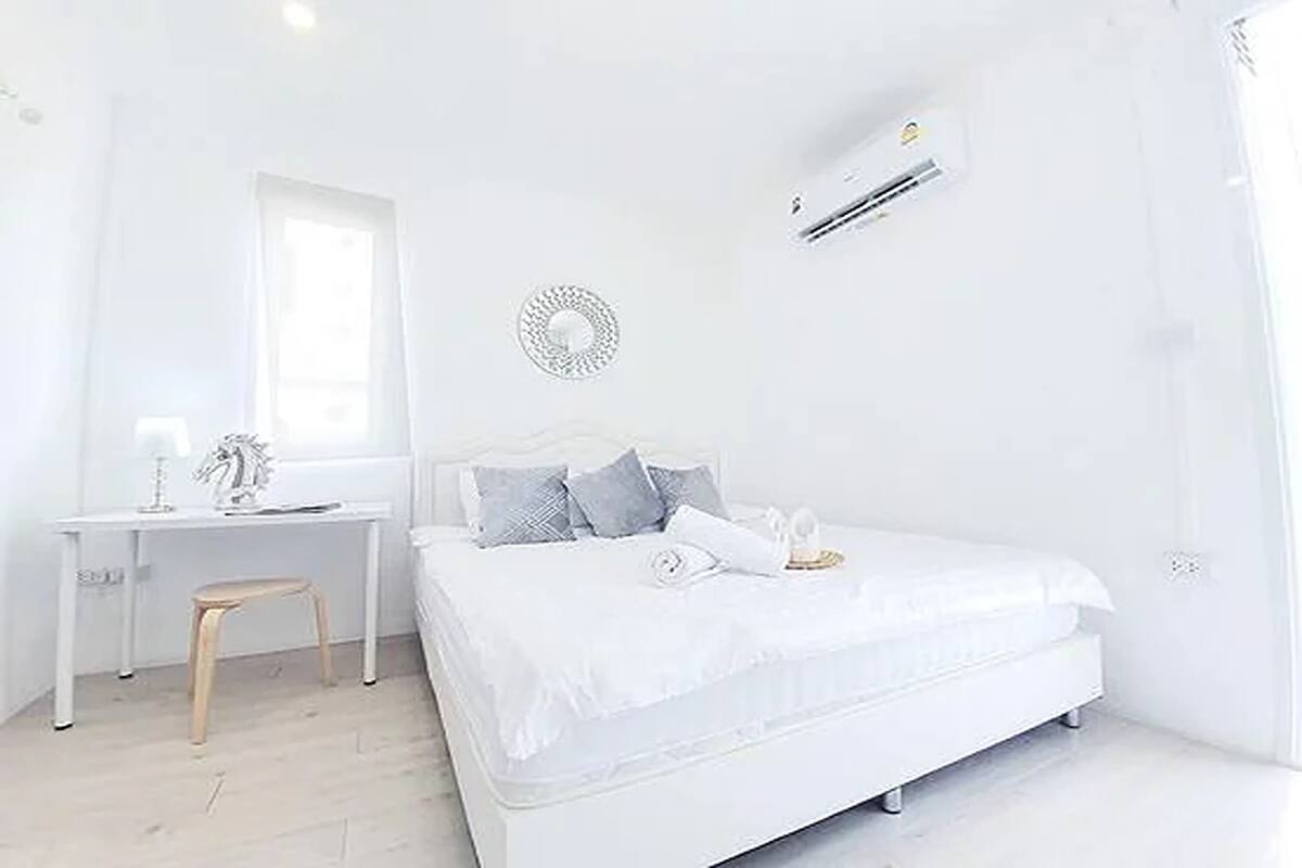 A white bedroom with a bed, a desk, and a chair.