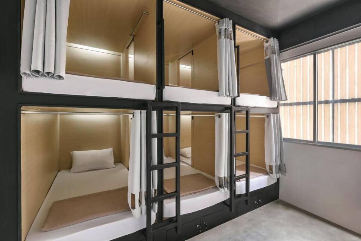 Een slaapkamer met stapelbed, raam, gordijnen en een houten hoofdbord.