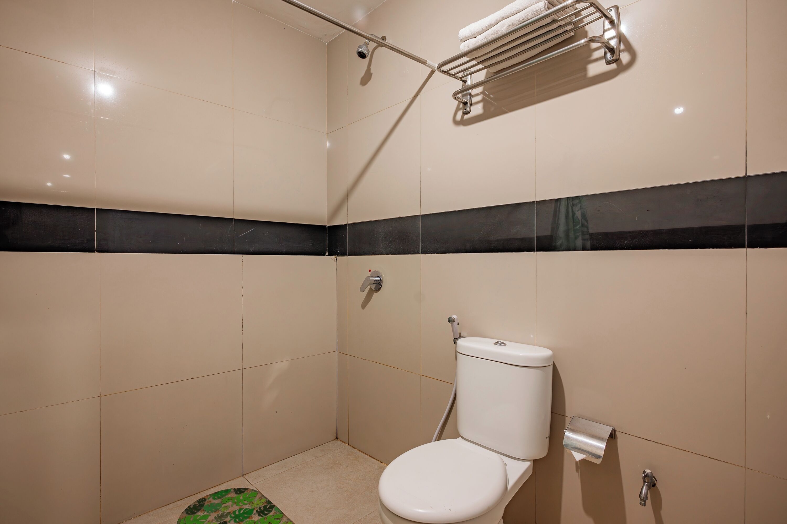 A small, modern bathroom with a toilet, a shower, and a towel rack.