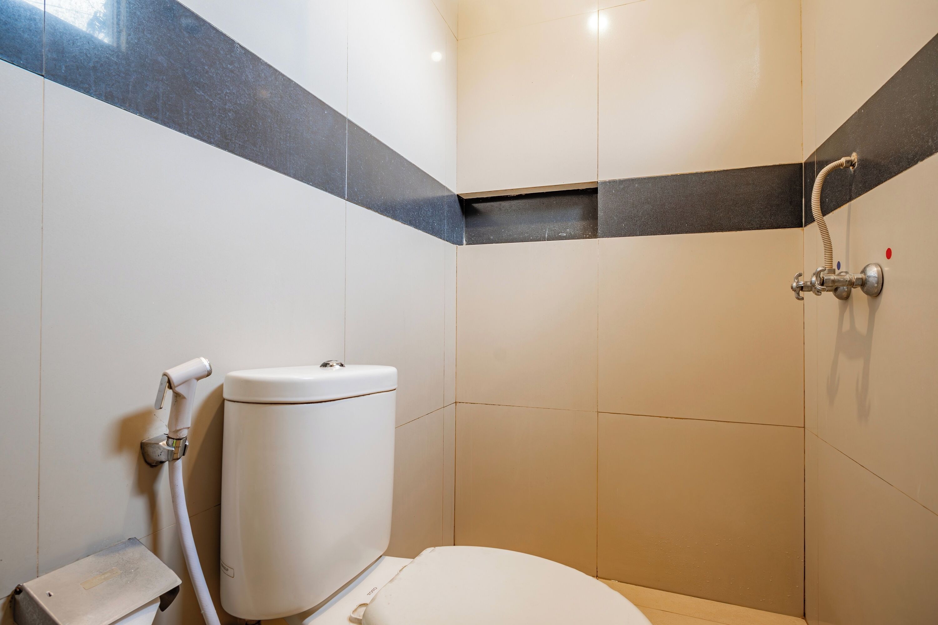 Un baño con inodoro, ducha y lavamanos empotrado.