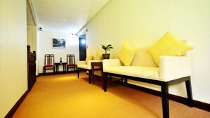 A hallway with a white sofa set, two chairs, a small table, and a potted plant. - Metro Vigan Inn - Annex (Vigan)