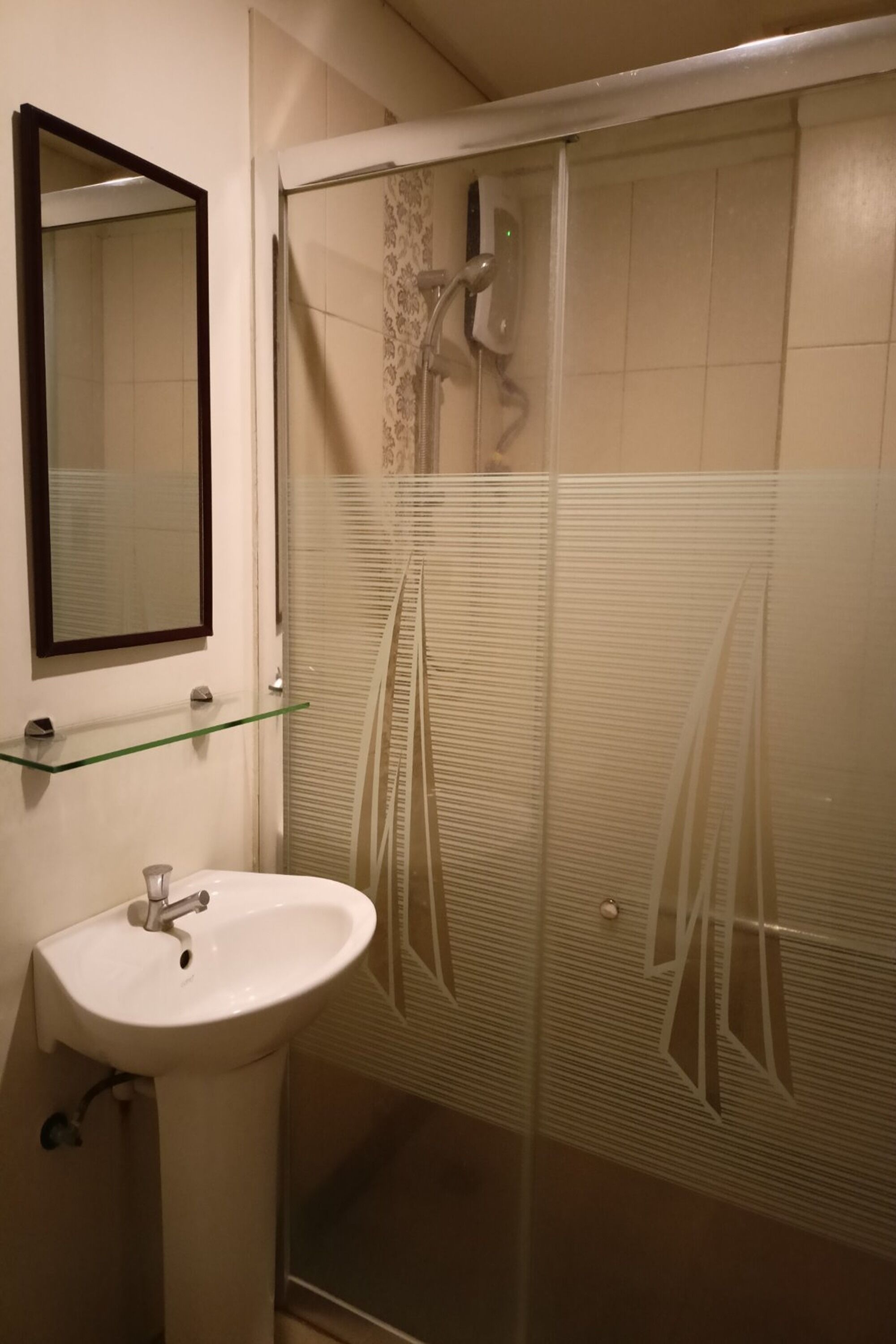 Un baño con cabina de ducha de vidrio, un lavabo blanco y un espejo en la pared.