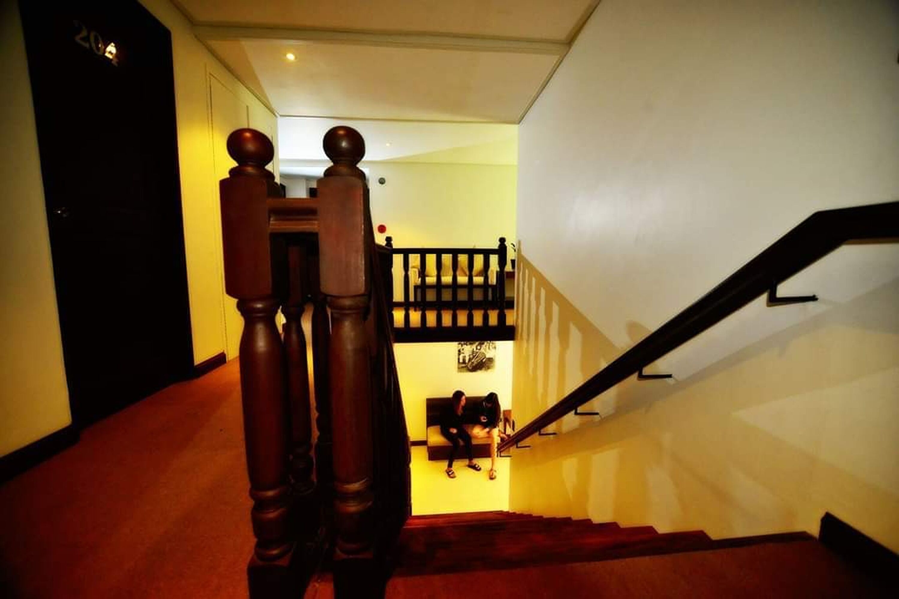 A staircase with wooden balusters and a handrail, leading to a landing with a bench.