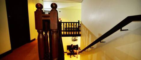 A staircase with wooden balusters and a handrail, leading to a landing with a bench.